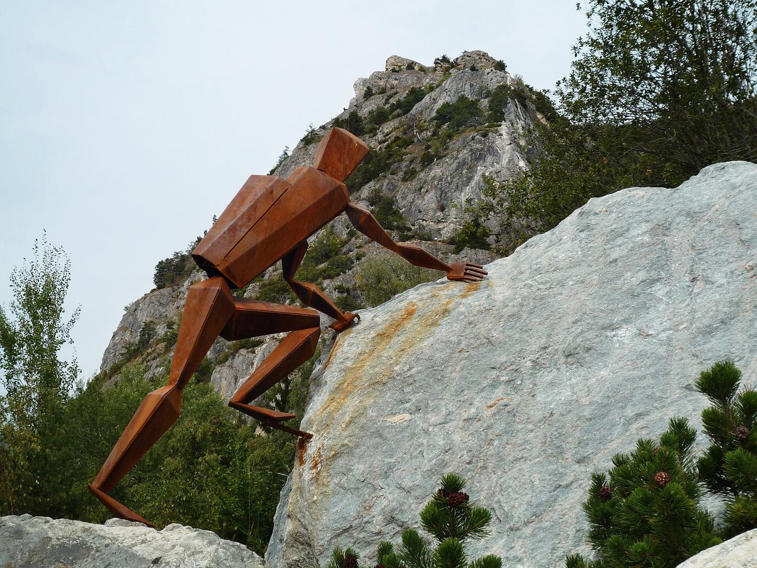 An iron climber on the access to the via ferrata on the rock head of Belvédère de Nax (in the background).